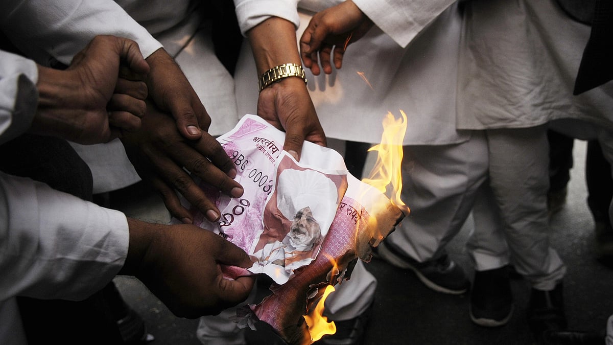 Protesters against demonetisation set fire to mock-ups of high-denomination currency, featuring Prime Minister Narendra Modi in place of Mahatma Gandhi, during a demonstration in Lucknow in 2016 (photo: Deepak Gupta/Hindustan Times via Getty Images)