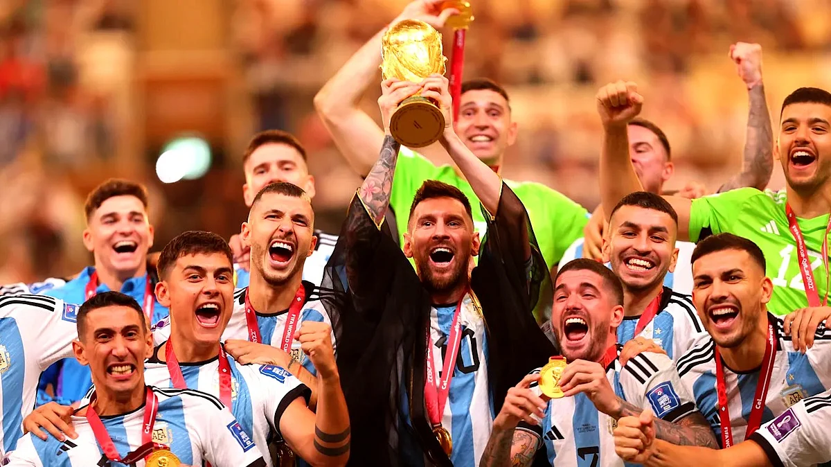 Lionel Messi holds aloft the FIFA World Cup 2022 with teammates (photo: Olympics.com)