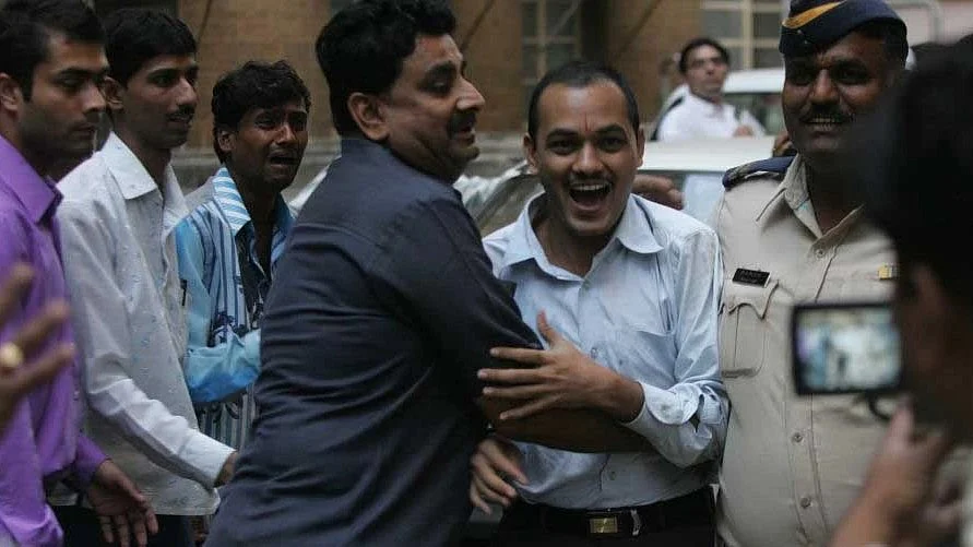 One of the men convicted of gangraping Bilkis Bano and assaulting her family as he is escorted away from the special court after the verdict of guilt. He can be seen laughing into the camera (photo: Kunal Patil/Hindustan Times via Getty Images)