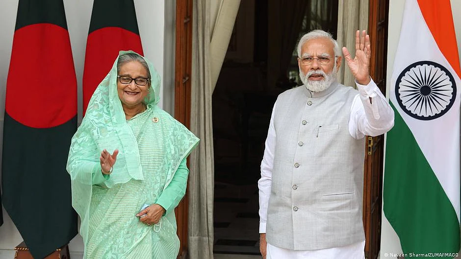File photo of Bangladesh prime minister Sheikh Hasina with her Indian counterpart Narendra Modi, both waving, each standing beside their national flag (photo: DW)