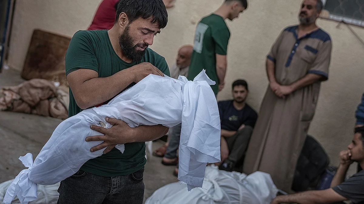 A man holds the shroud-wrapped body of a child. Over 14,000 of Gaza’s 1.1 million children have been killed by Israeli forces since 7 October 2023 (photo courtesy @motaz_azaiza/Instagram)