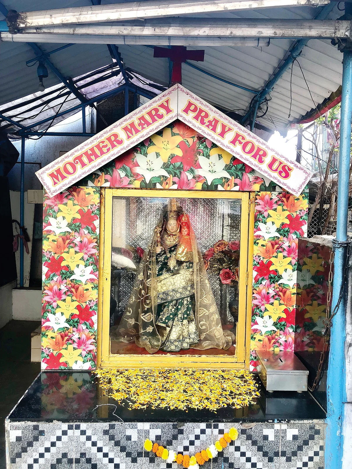 The shrine of the Virigin Mary, who is draped each week by a Hindu woman and feted with marigolds, same as any Hindu deity, stands not far from a Hanuman Mandir