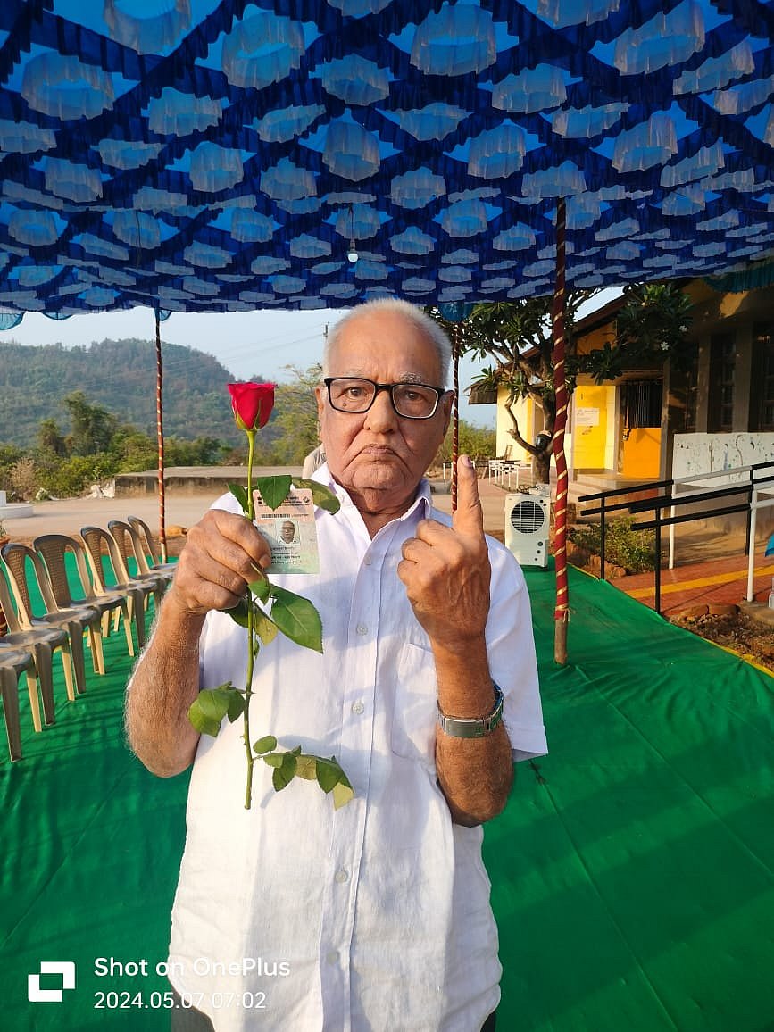 A senior citizen holds up his voter ID card, marked index finger and a red rose (photo courtesy @ECISVEEP/X)