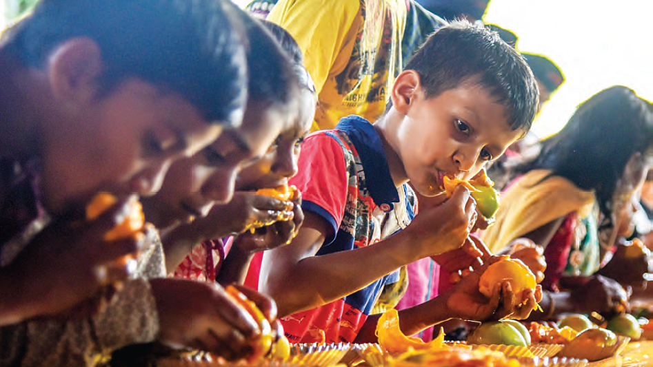 Children enjoy mangoes at a party (photo: Getty Images)