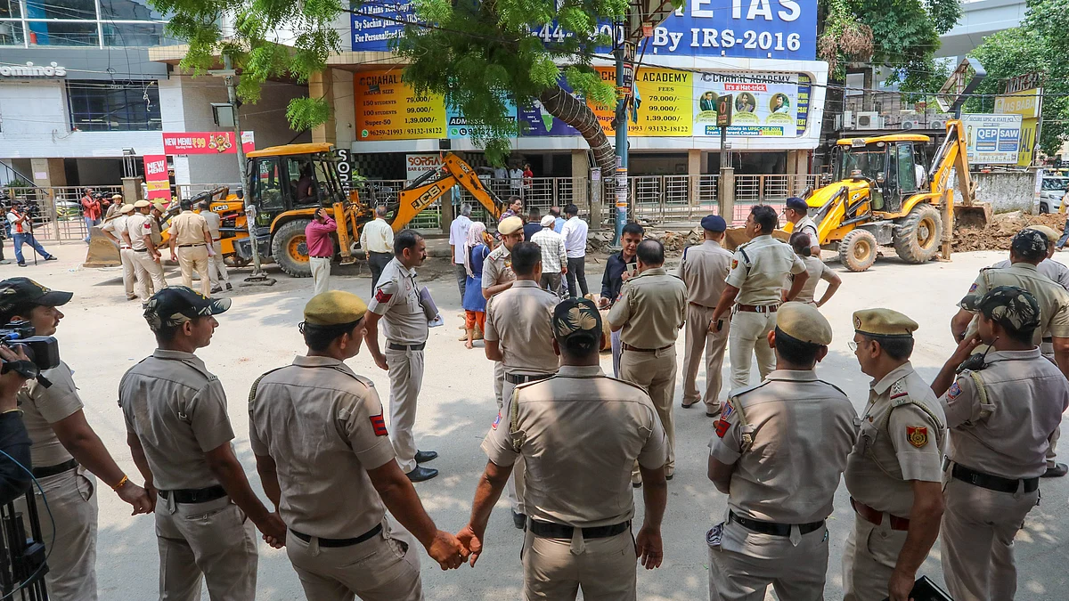Policemen guard as bulldozers demolish parts of IAS coaching institute on 29 July (photo: PTI)