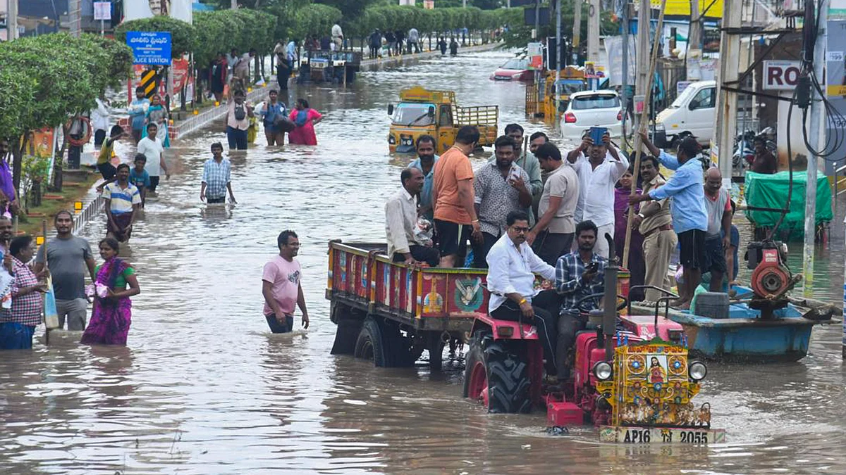 Andhra Pradesh: People cross a waterlogged street in Vijayawada