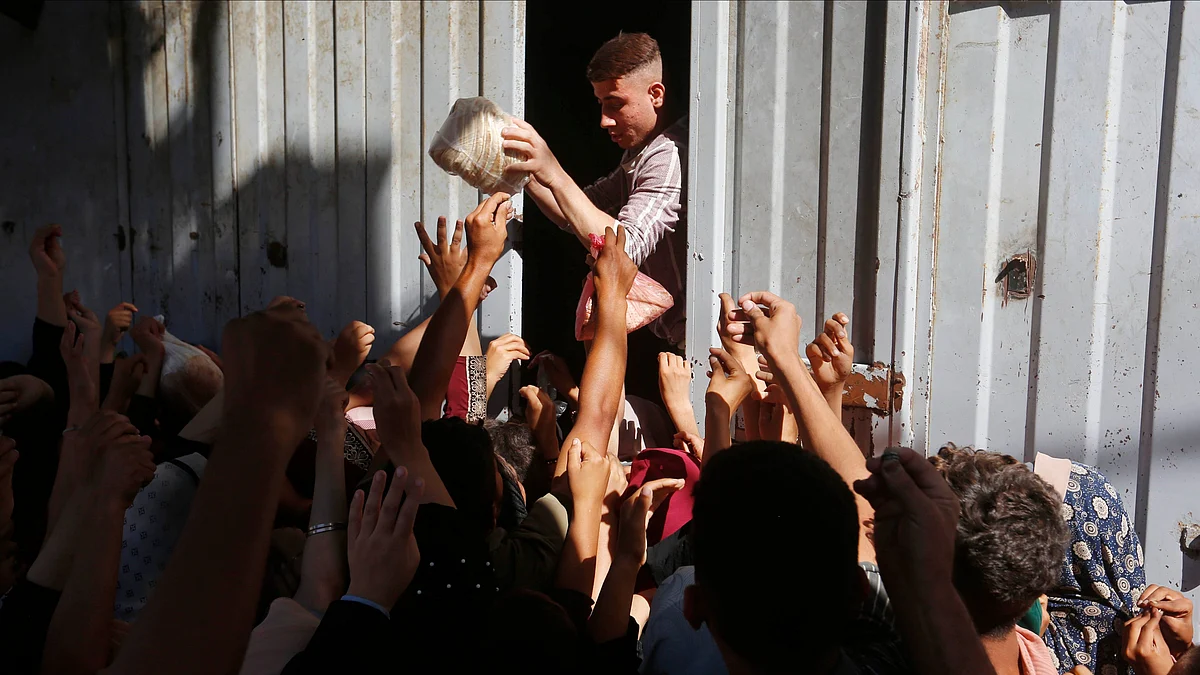 People struggle to get a loaf of bread from an aid truck in Deir al-Balah, Gaza.