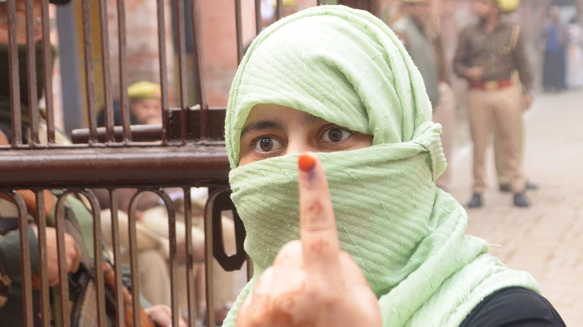 A voter shows her ink-marked finger after casting a vote in Sisamau, UP
