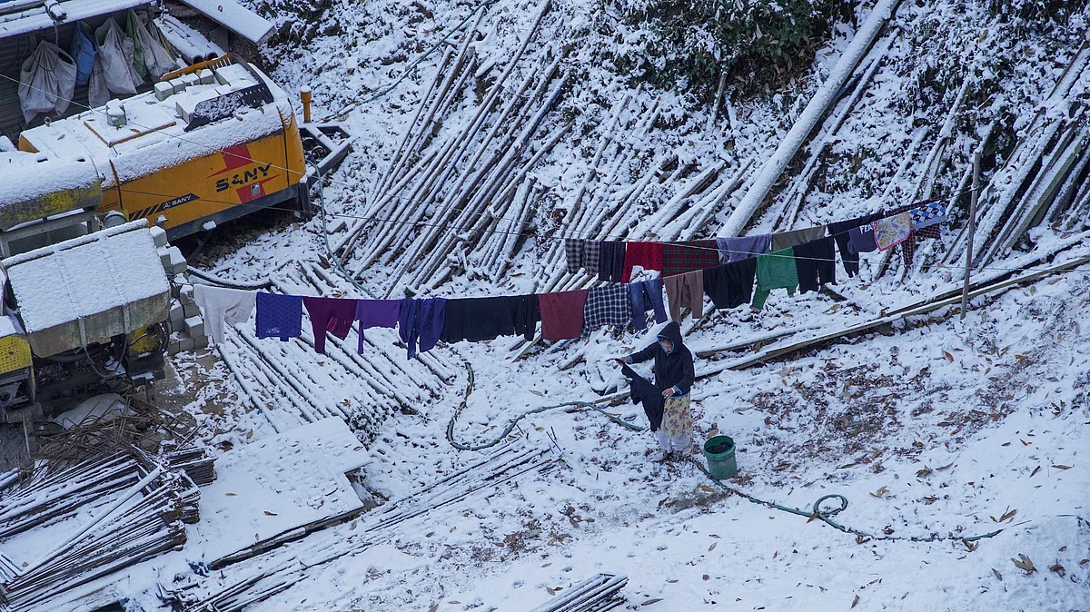 A person hanging clothes despite the snow