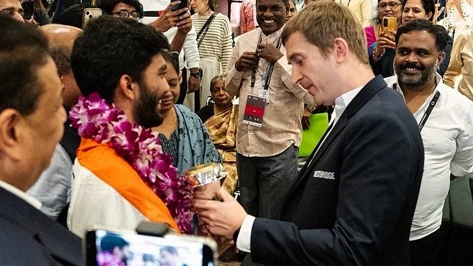 Polish GM Grzegorz Gajewski admires Gukesh's trophy in Singapore (photo: @GajuChess/X)