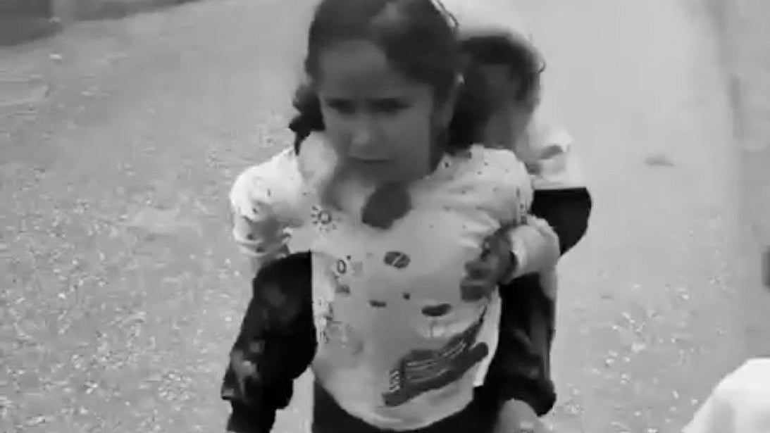 Rafah, 2024: A young child carries her sibling piggyback as the family seek a 'safe place' in Gaza