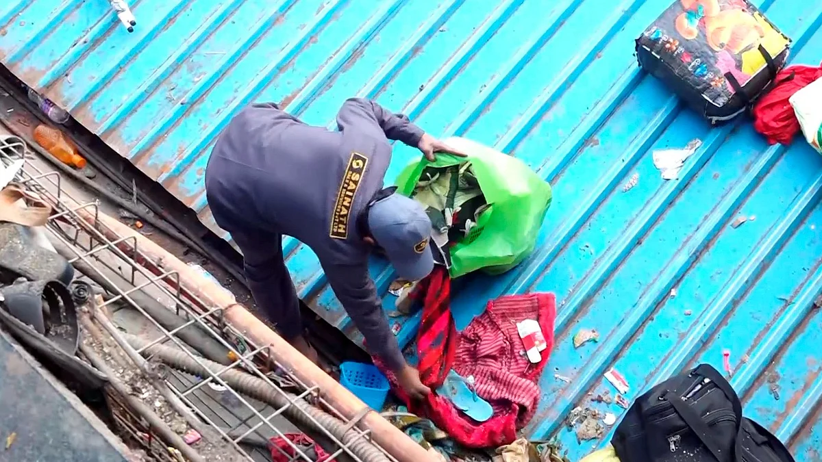Cleaning staff collects belongings of passengers at New Delhi station on 16 Feb (photo: PTI)