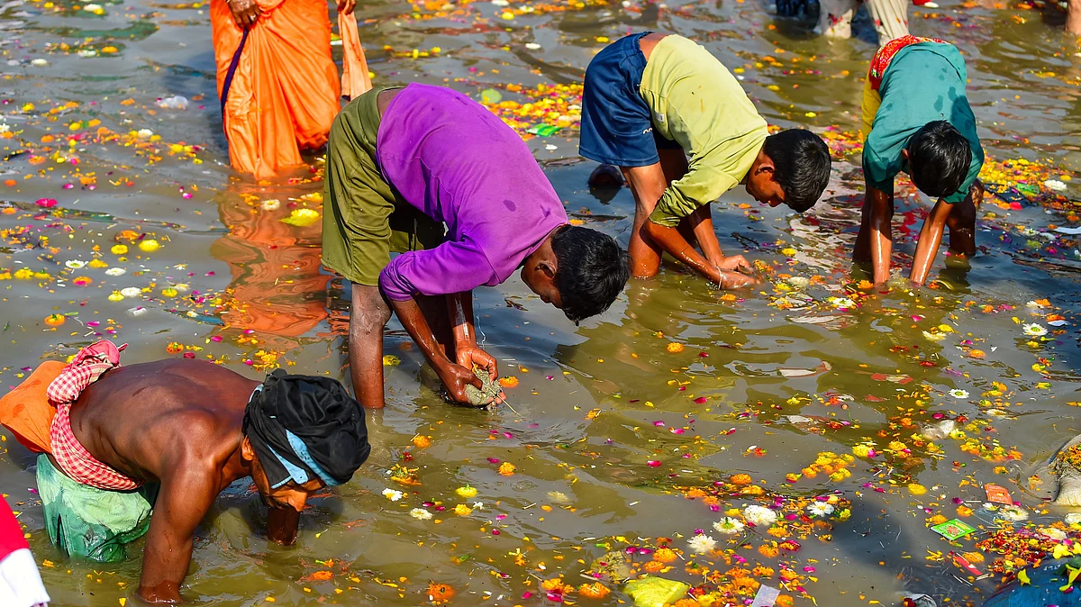 Children hunt for valuables from accumulated materials at the Sangam, in Prayagraj (photo: PTI)