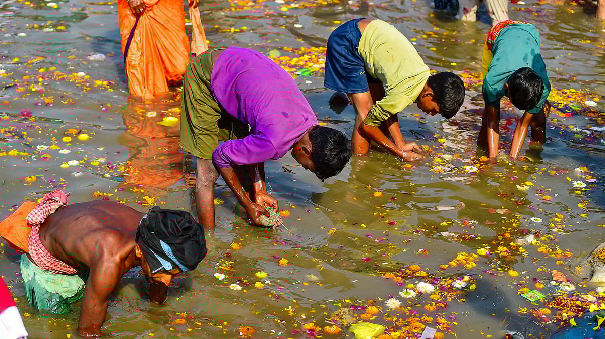 Children hunt for valuables from accumulated materials at the Sangam, in Prayagraj (photo: PTI)