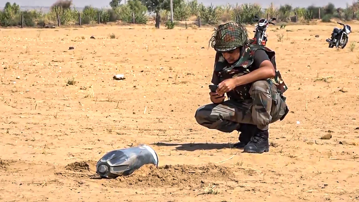 A security personnel inspects an unidentified projectile in Jaisalmer on 10 May (photo: PTI)