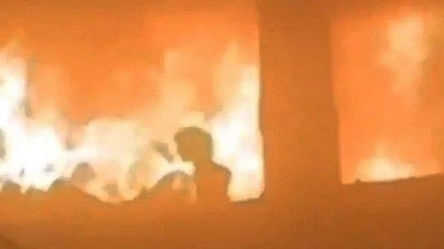 A young child trapped by flames looks for a way to escape the burning school building 