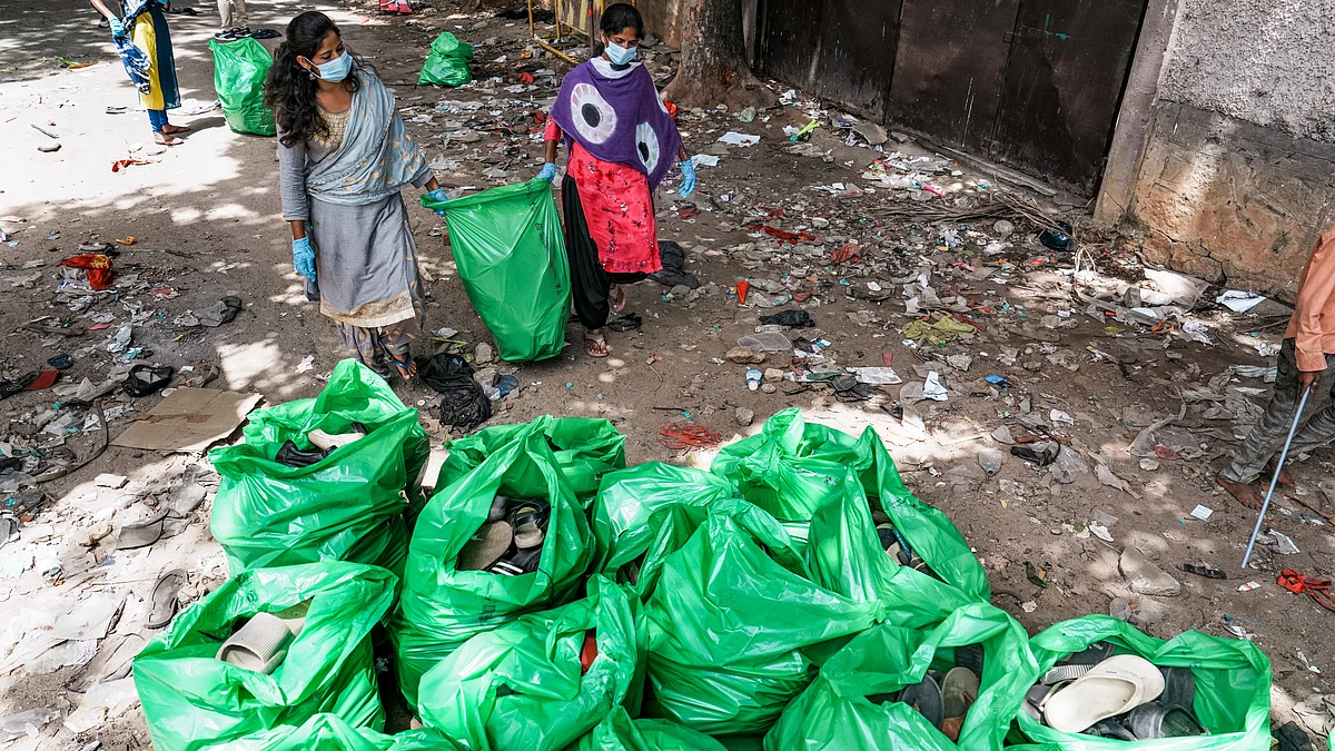 Workers remove footwear lying near Gate No. 7 of Chinnaswamy Stadium on 5 June (photo: PTI)