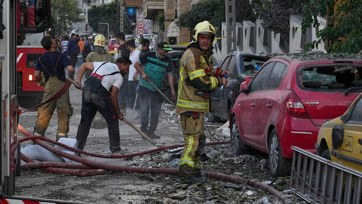 Firefighters and people clean up the scene after Israeli strikes in Tehran on 13 June (photo: AP/PTI)