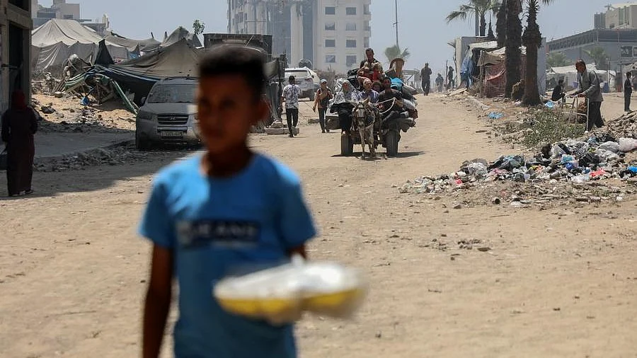 Mohammad Abu Ouda carries food at temporary shelter in Gaza City on 9 June (photo: Xinhua/IANS)