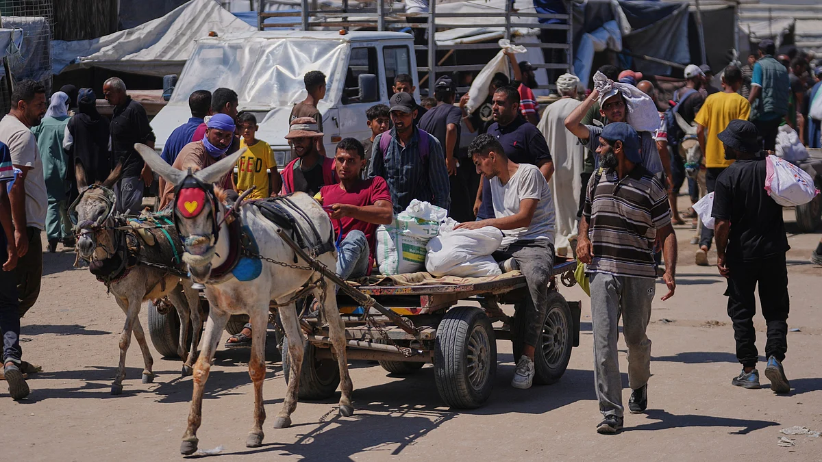 Palestinians carry bags containing food and humanitarian aid in Rafah on 25 June (photo: AP/PTI)
