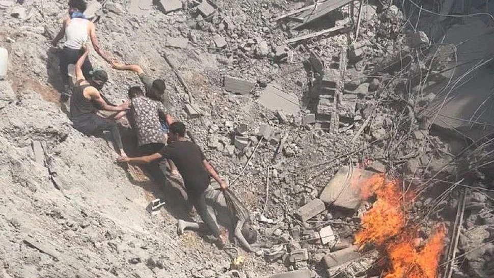 Palestinians try to pull each other out of the crater from a bombing of refugee tents