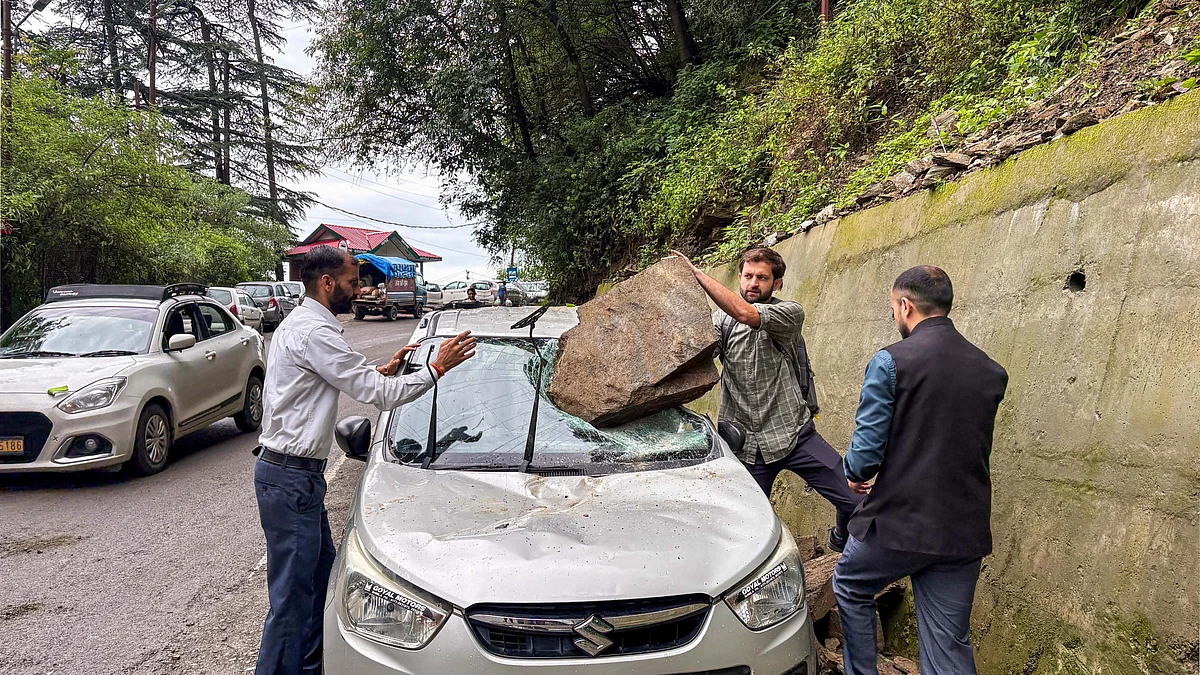 people trying to remove a boulder that damaged a car after rainfall in Shimla. (photo: PTI)
