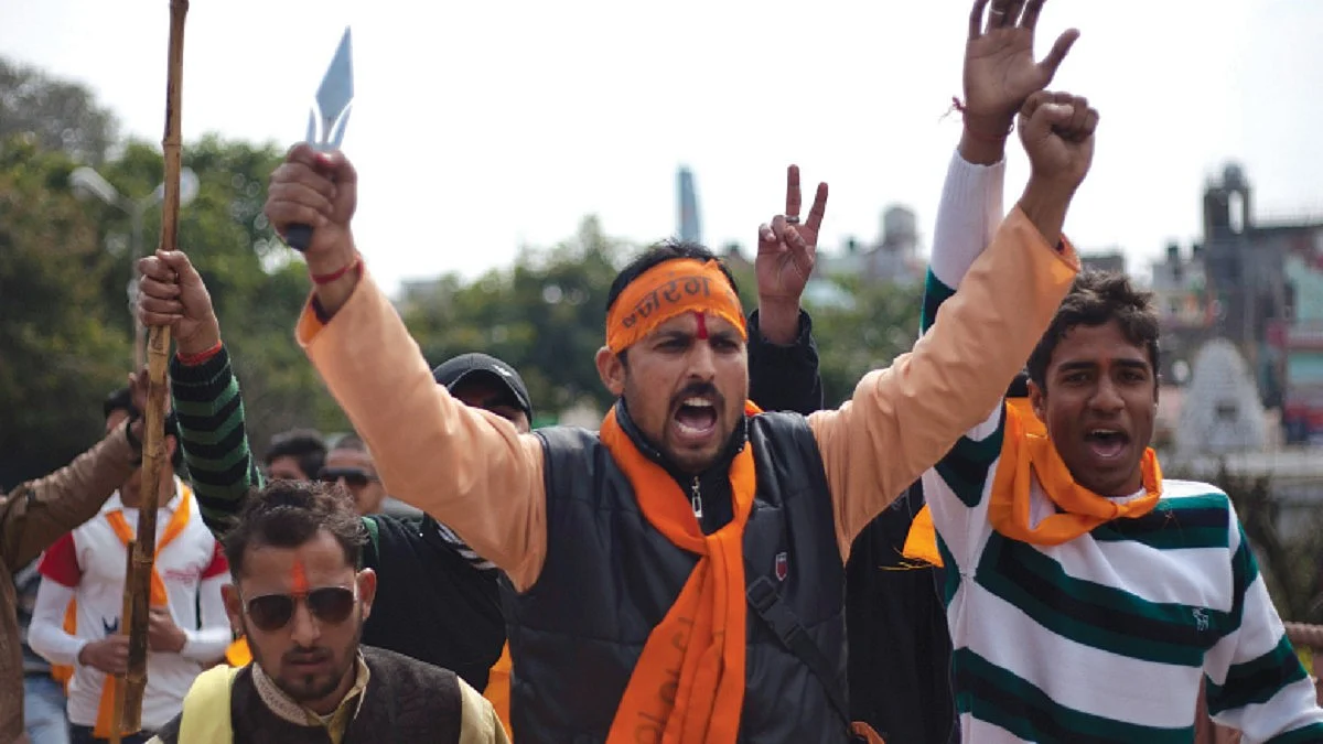 A Hindutva activist brandishes a small sharp trident in a demonstration, where others hold up staves