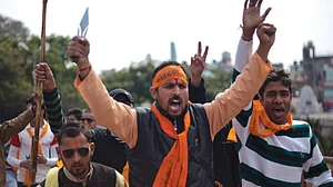A Hindutva activist brandishes a small sharp trident in a demonstration, where others hold up staves