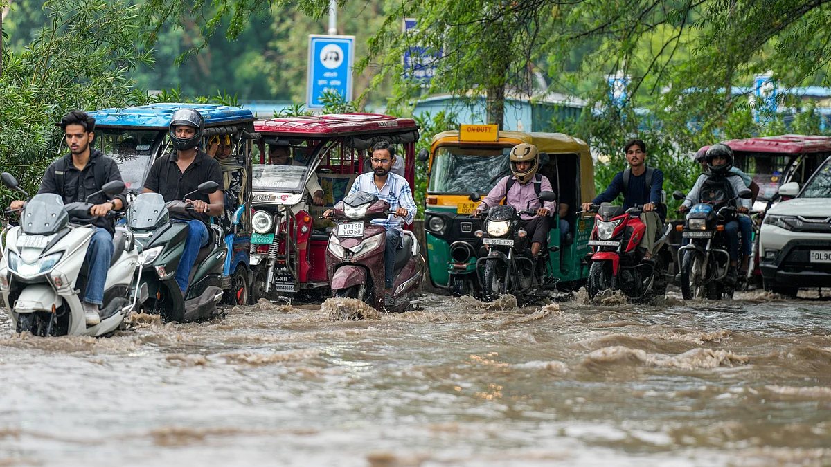 Commuters wade through a waterlogged road in New Delhi on 22 July (photo: PTI)