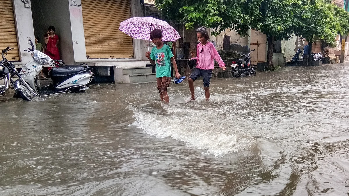 Children struggle through a water-logged street in Rajasthan's Bhilwara (photo: IANS)