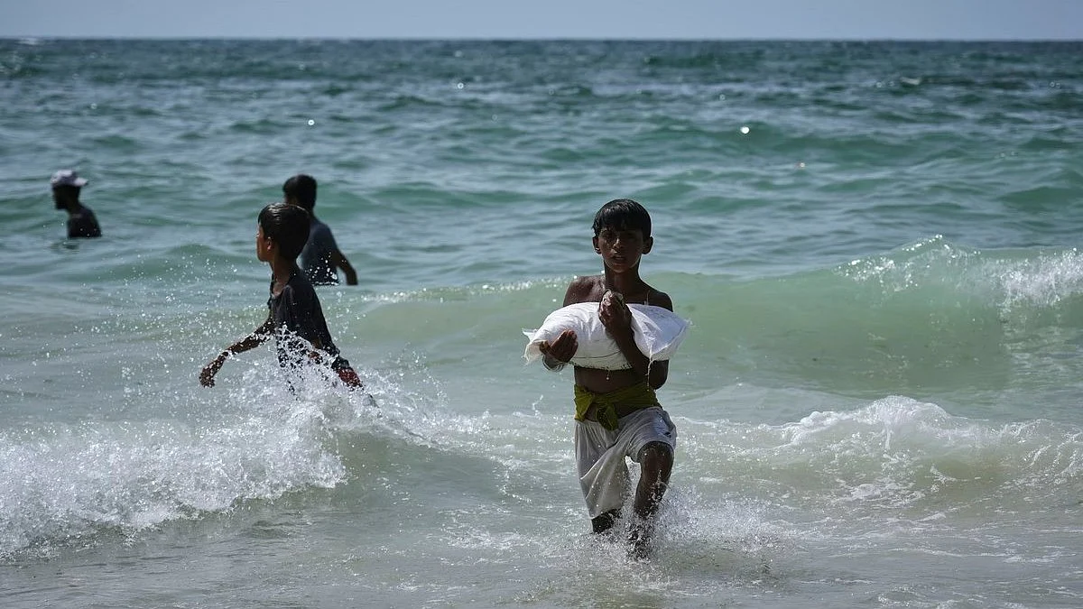 Children retrieve sacks of aid supplies from the sea, where air drops landed (Zawaida, 29 July 2025)