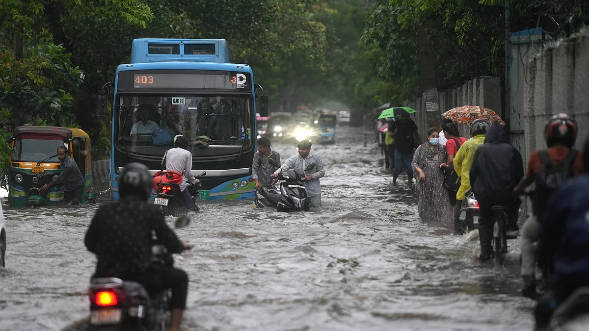 Commuters wade through a waterlogged road amid heavy rain in New Delhi on 14 August
