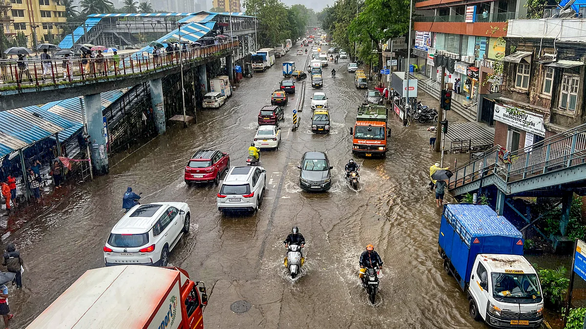 Commuters wade through a waterlogged road in Mumbai on 18 August