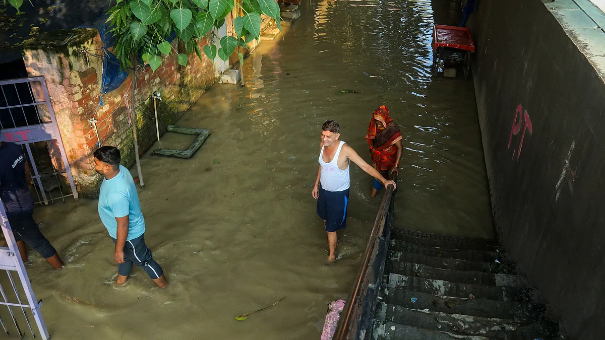 Locals walk through an area inundated by the swollen Yamuna river at Yamuna Bazar