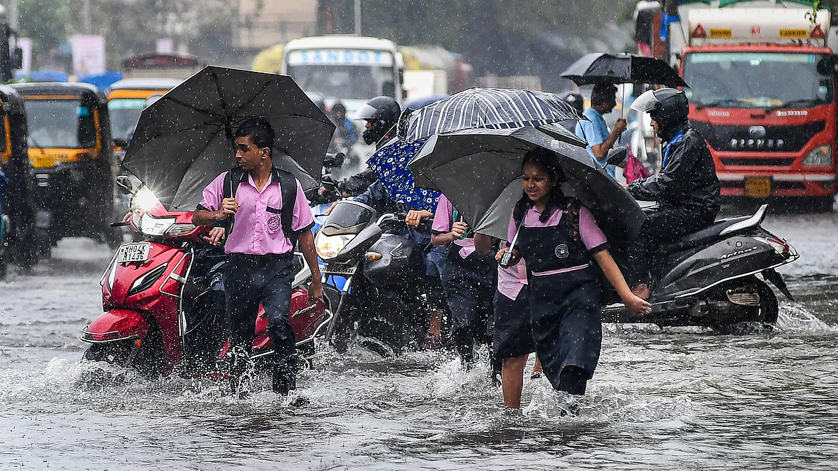 Commuters make their way through a waterlogged road in Mumbai
