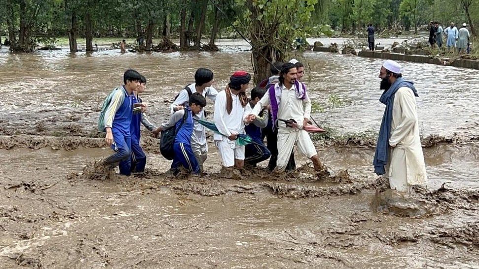 People wade through a flooded road in Buner, Khyber Pakhtunkhwa 