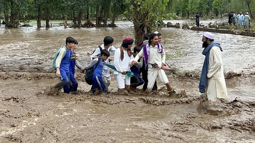 People wade through a flooded road in Buner, Khyber Pakhtunkhwa