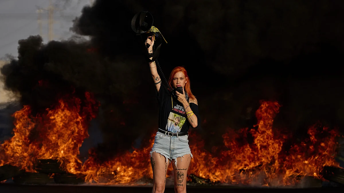 An activist blocks a highway in Israel during a protest near the city of Lod, 26 Aug