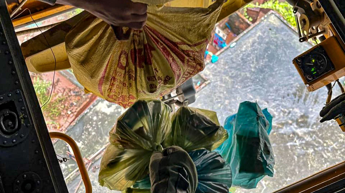 Relief materials being dropped from a helicopter at a flood-affected area.