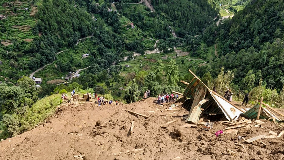 People gather as rescue operations continue at a landslide site in Kullu