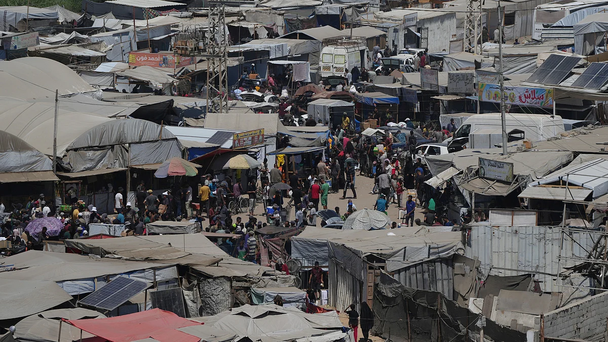 Displaced Palestinians walk through a makeshift tent camp in Khan Younis