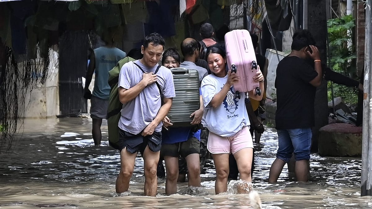 Delhiites carry suitcases through the flooded Monastery market, near ISBT, Delhi