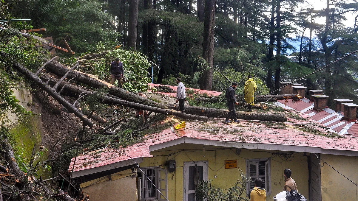 Locals stand near a house damaged due to landslide in Bilaspur