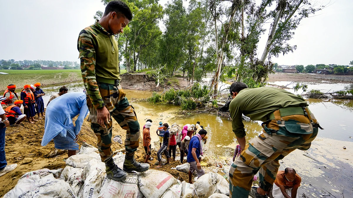 Security personnel and volunteers use sandbags to repair a broken embankment in Amritsar district