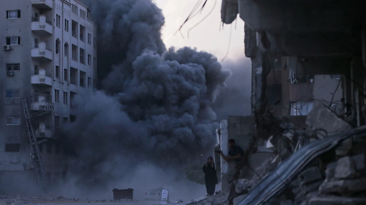 Women stop in shock as a high-rise sinks under Israeli bombardment in Gaza City