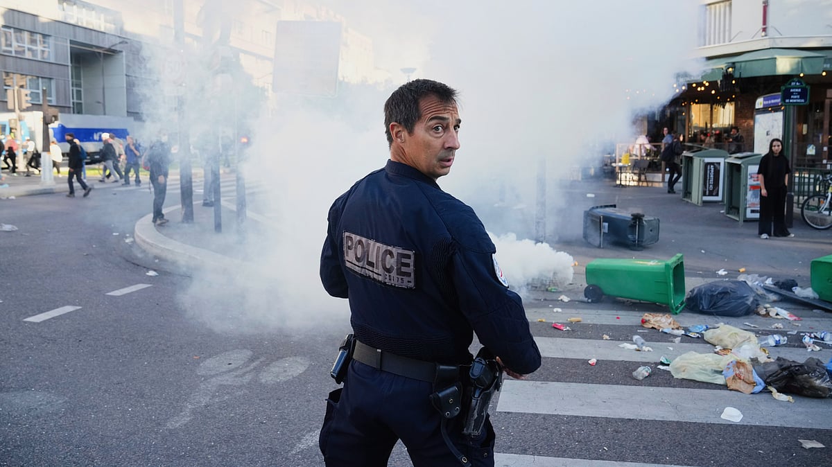 A police officer stands next to bins placed on a street to block it in Paris, 10 Sept