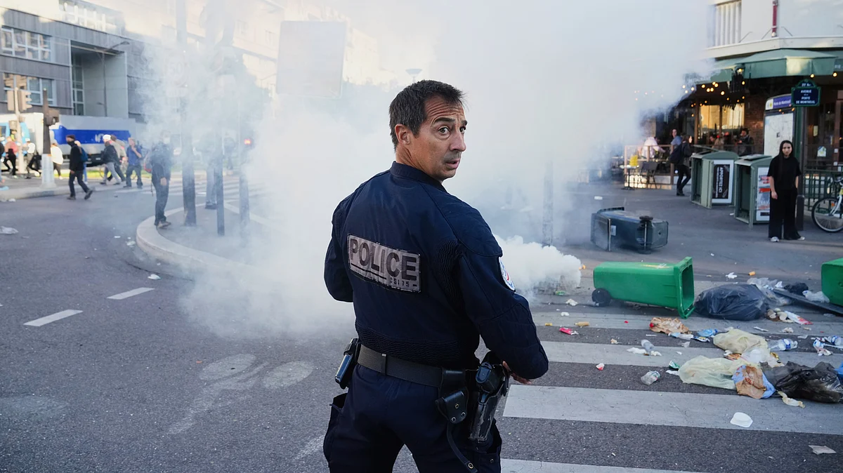 A police officer stands next to bins placed on a street to block it in Paris, 10 Sept