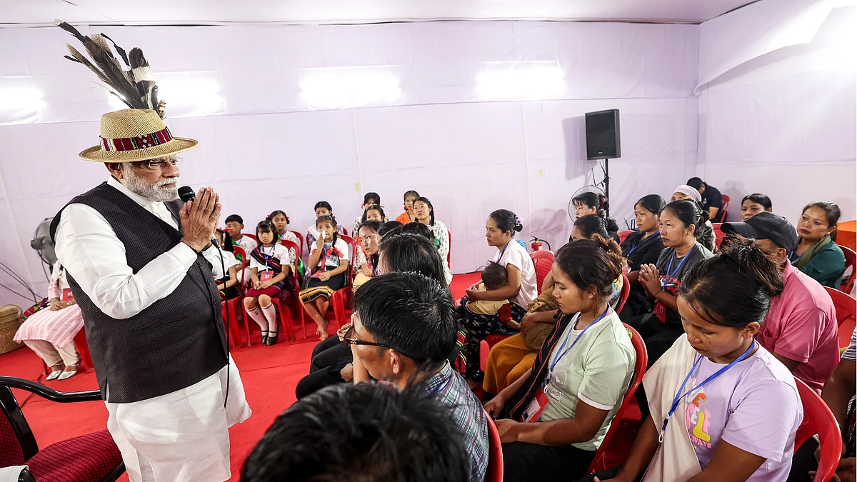 Befeathered PM Modi folds his hands before residents of a Churachandpur relief camp