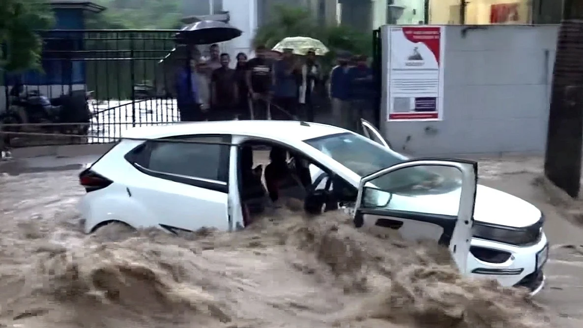 A car is submerged on a flooded road in Dehradun after heavy rains trigger a cloudburst.