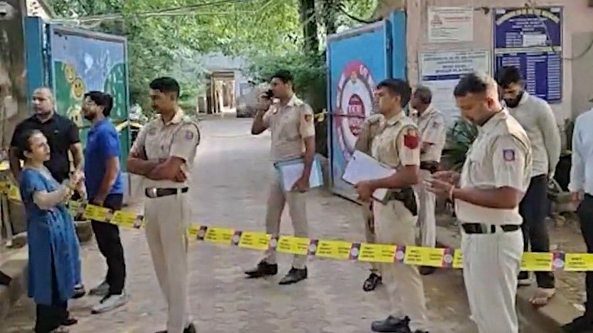 Police stand guard outside a Delhi school following a bomb threat.